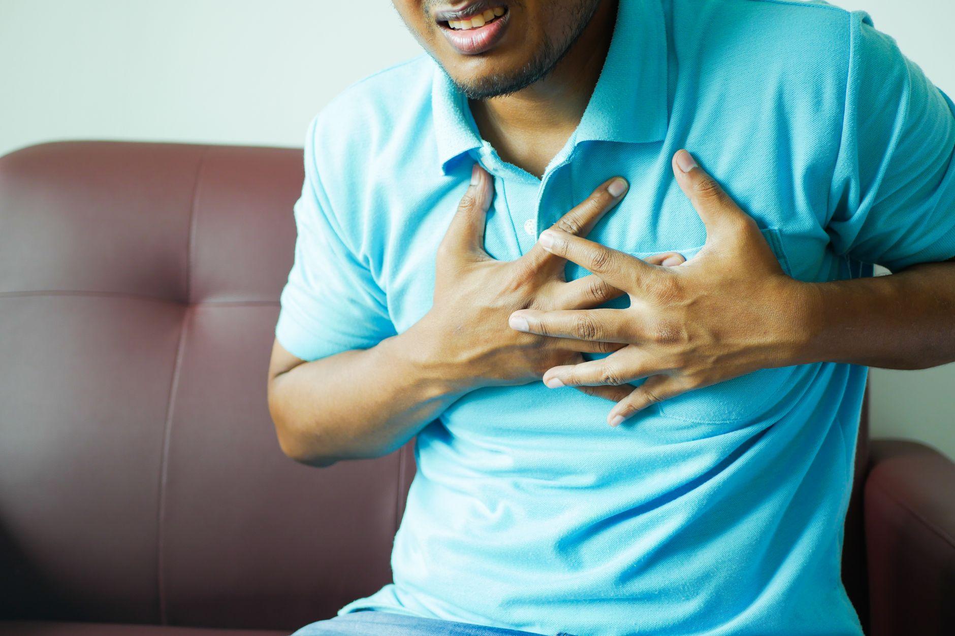 A person clutching their chest in pain, representing critical heart attack symptoms and the need for urgent care.