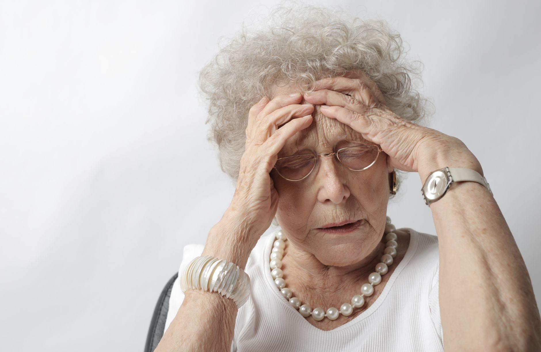 An older person struggling to manage complex financial documents and receipts at a desk.
