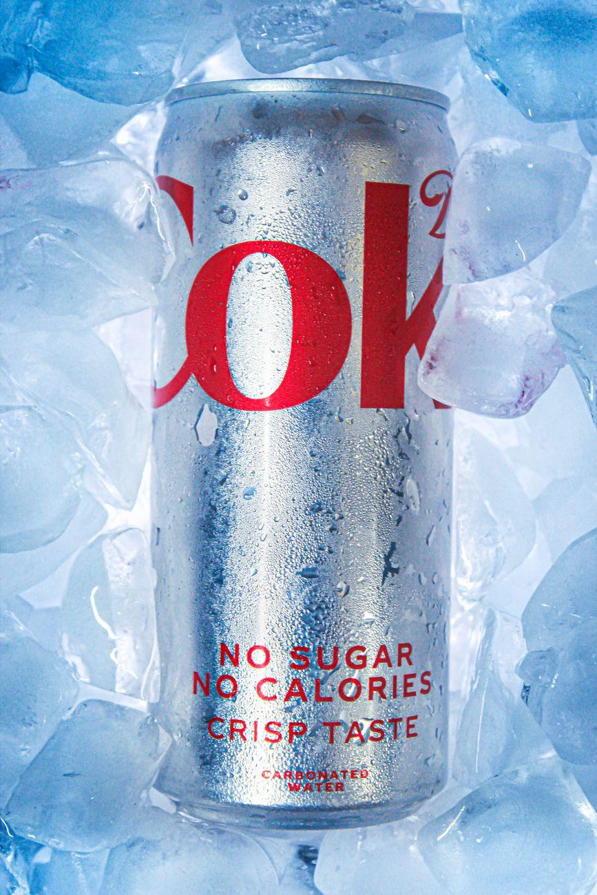 A glass of diet soda next to a stylized illustration of a human brain, representing diet soda side effects.